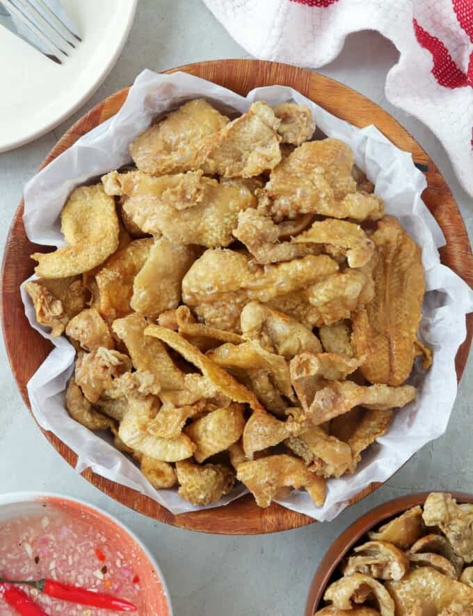 Chicken Skin Chicharon in a white serving bowl with spicy vinegar on the side.