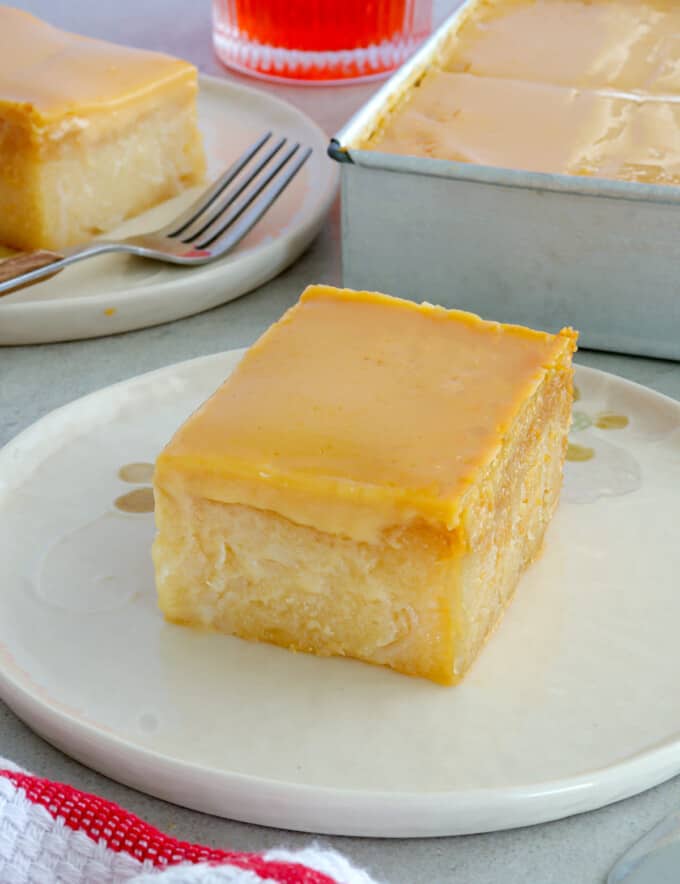 slice of cassava cake with custard topping on white serving plate.